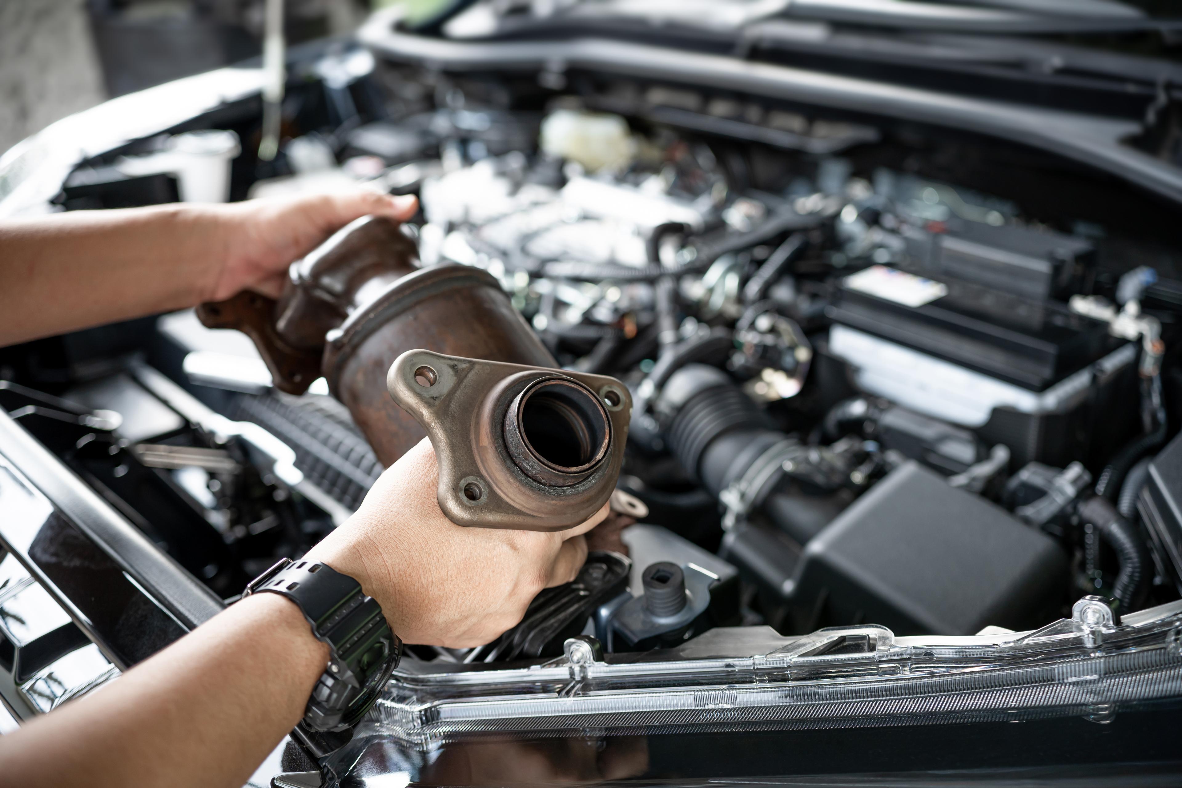 Hands holding an old catalytic converter