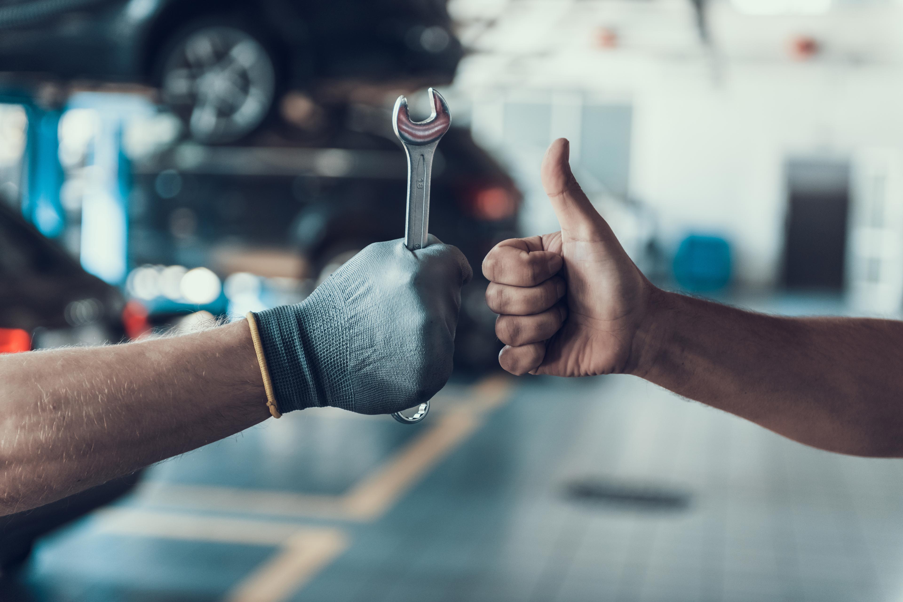 Thumbs up holding a wrench