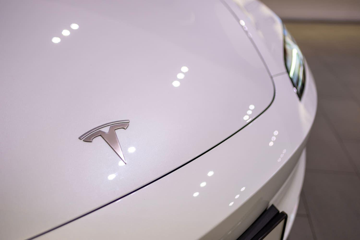 Close up of a Tesla badge on a white car