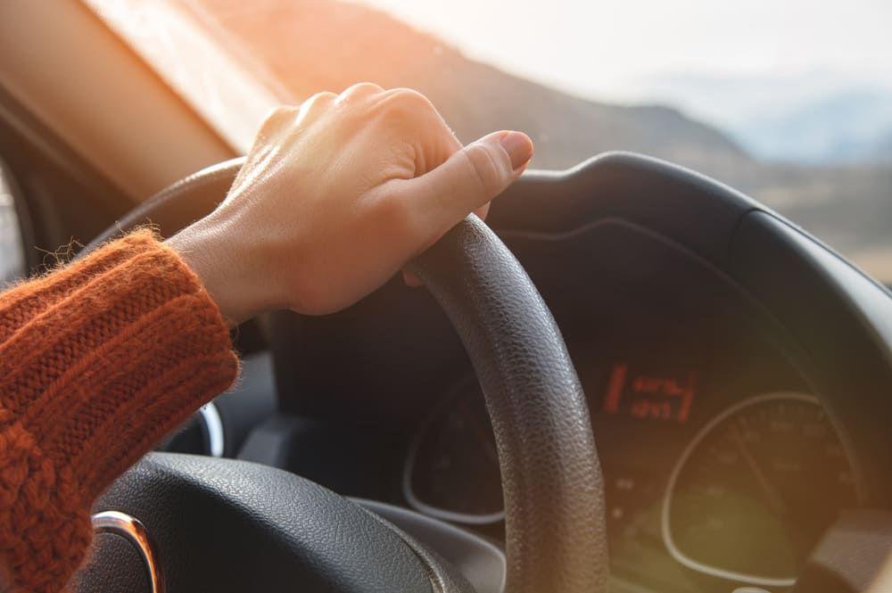Close up of driver's hand on steering wheel