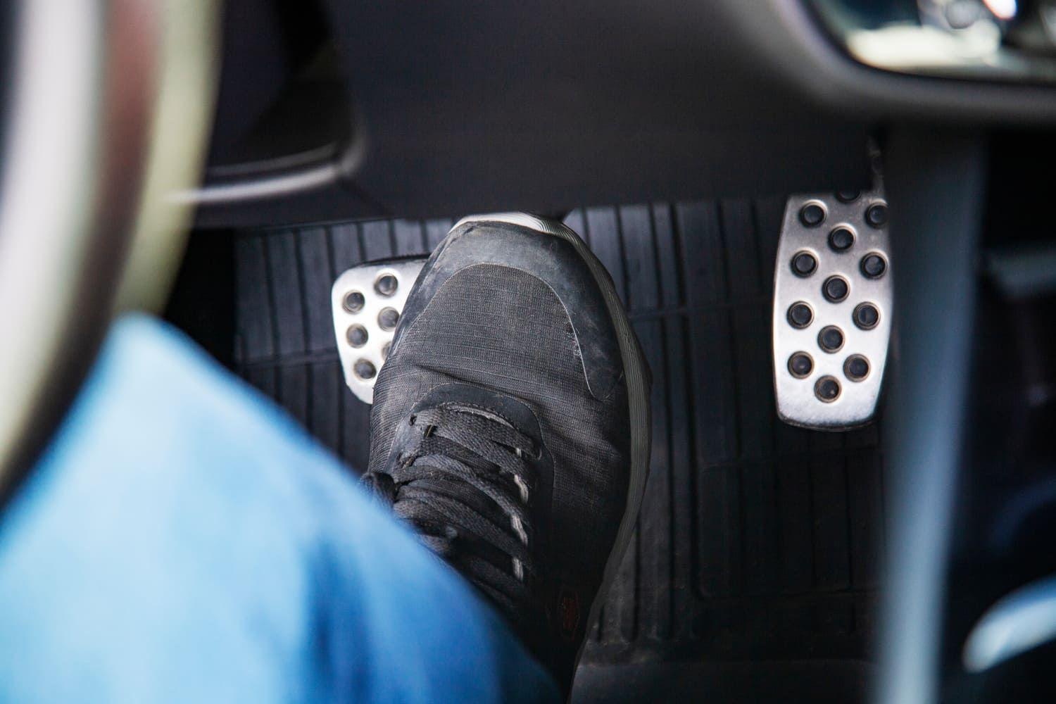 Driver in blue jeans pressing down on a clutch pedal